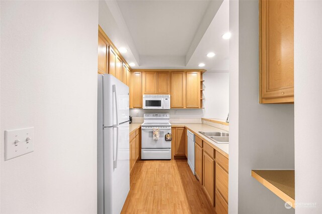 kitchen with light wood-type flooring, white appliances, and sink