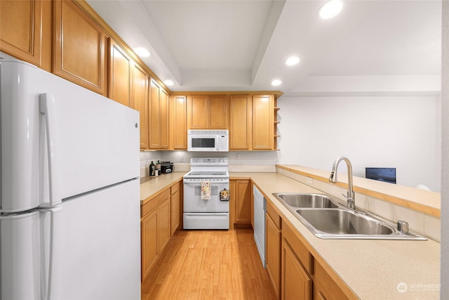 kitchen with a raised ceiling, white appliances, sink, and light hardwood / wood-style flooring