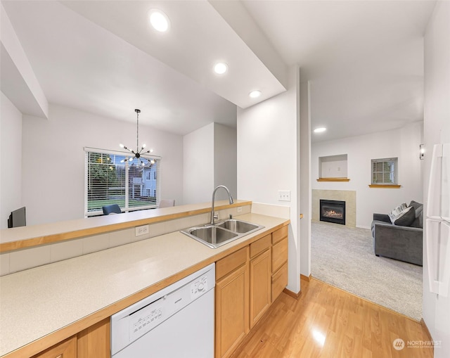 kitchen featuring a fireplace, sink, light hardwood / wood-style flooring, a notable chandelier, and dishwasher