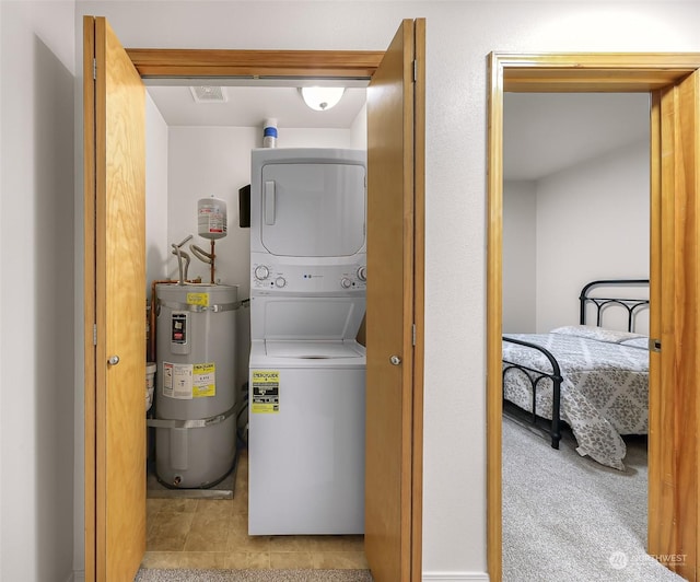 laundry room with light tile patterned flooring, strapped water heater, and stacked washer and dryer