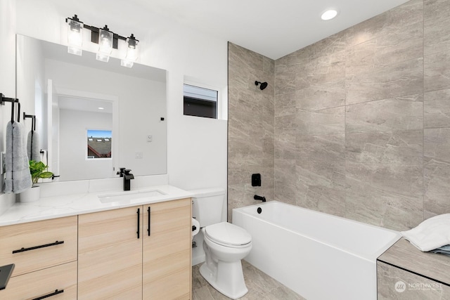 full bathroom featuring tiled shower / bath, vanity, and toilet