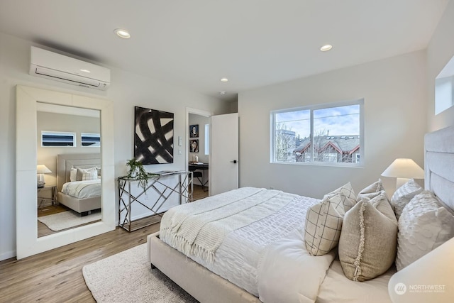 bedroom featuring hardwood / wood-style floors and an AC wall unit