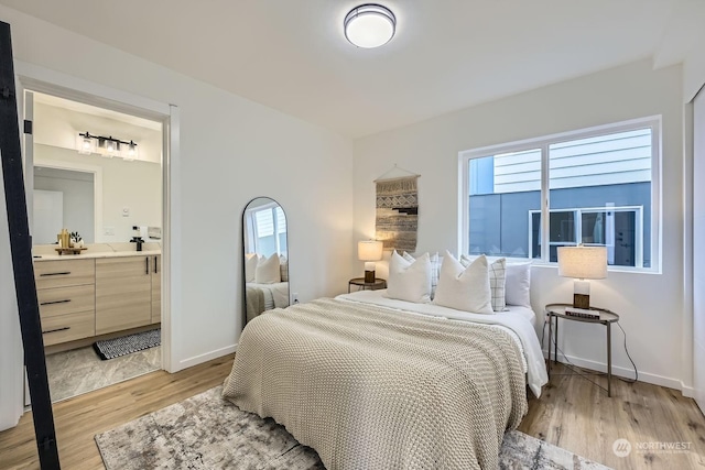 bedroom with ensuite bath and light hardwood / wood-style flooring