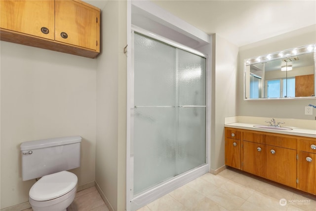 bathroom with tile patterned flooring, vanity, a shower with shower door, and toilet