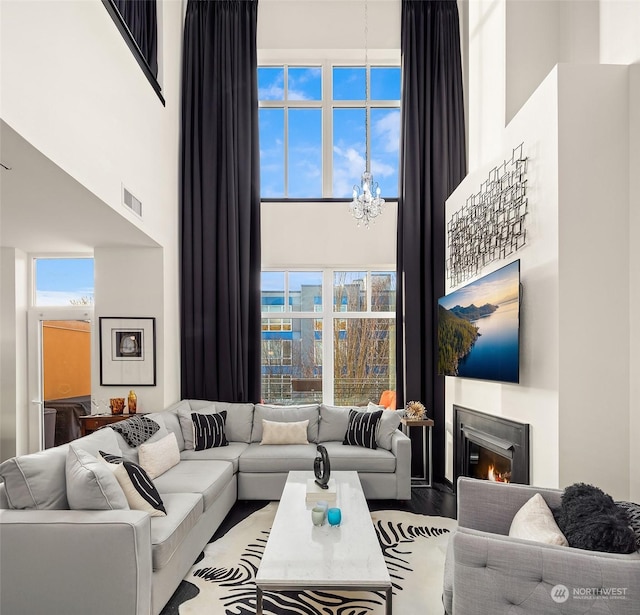 living room featuring a towering ceiling, a chandelier, and light wood-type flooring