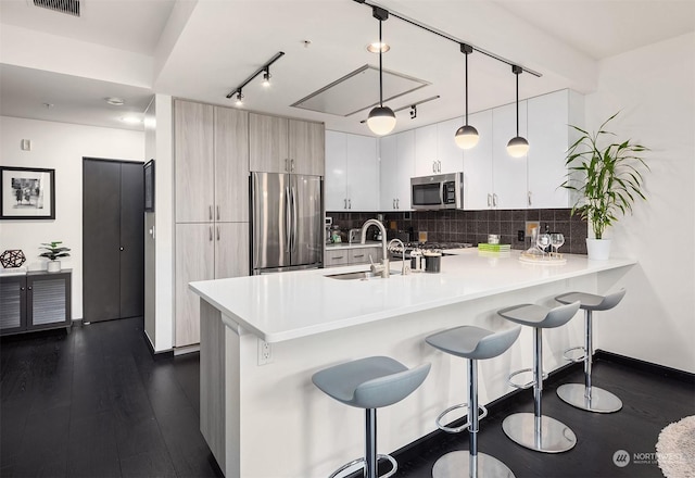 kitchen with kitchen peninsula, backsplash, stainless steel appliances, dark wood-type flooring, and hanging light fixtures