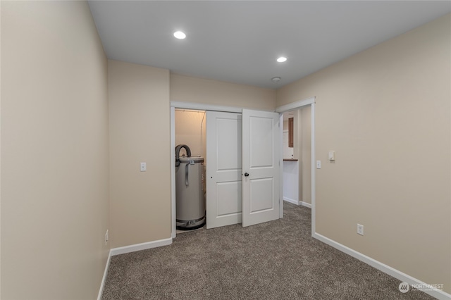 unfurnished bedroom with carpet floors, a closet, and water heater