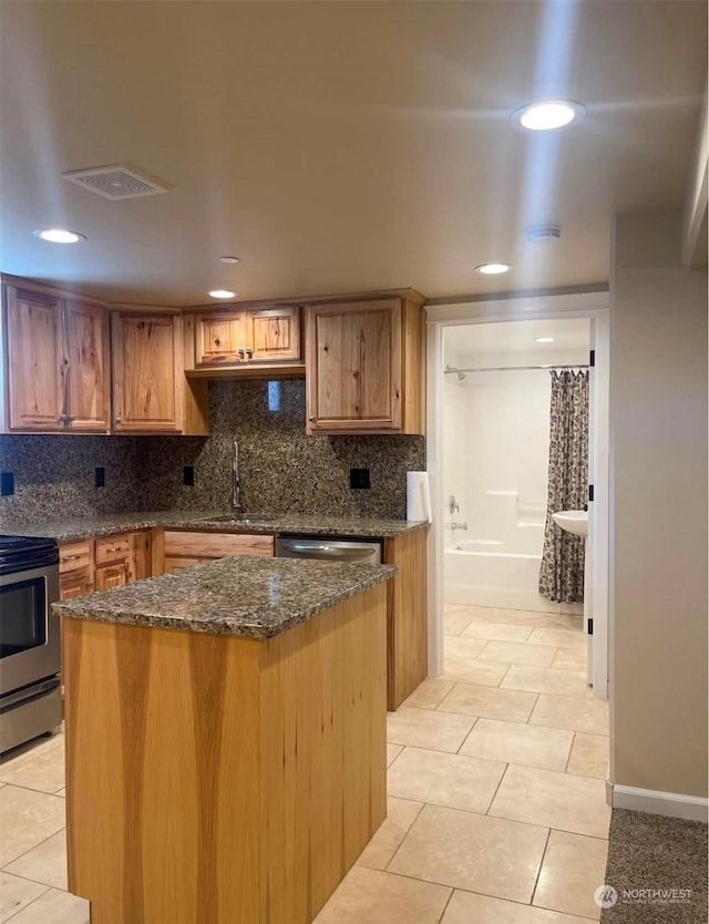 kitchen with backsplash, sink, a kitchen island, and stainless steel appliances