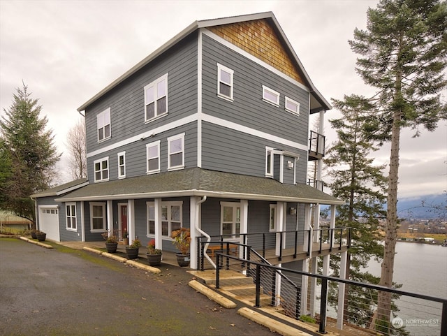 view of front of home featuring a porch, a garage, and a water view