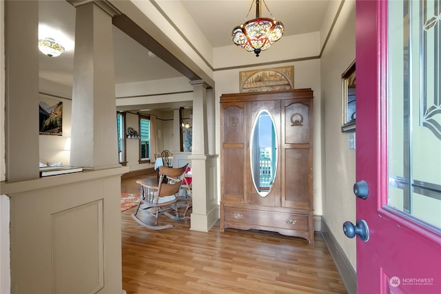 foyer featuring decorative columns, a notable chandelier, and light hardwood / wood-style floors