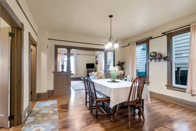 dining area featuring hardwood / wood-style floors, decorative columns, and a notable chandelier