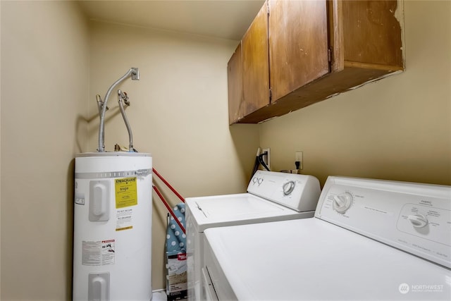 clothes washing area featuring cabinets, electric water heater, and washer and clothes dryer