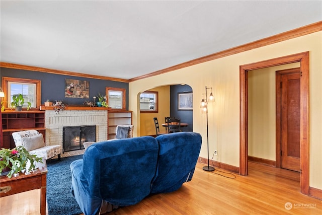 living room with hardwood / wood-style flooring, a brick fireplace, and ornamental molding