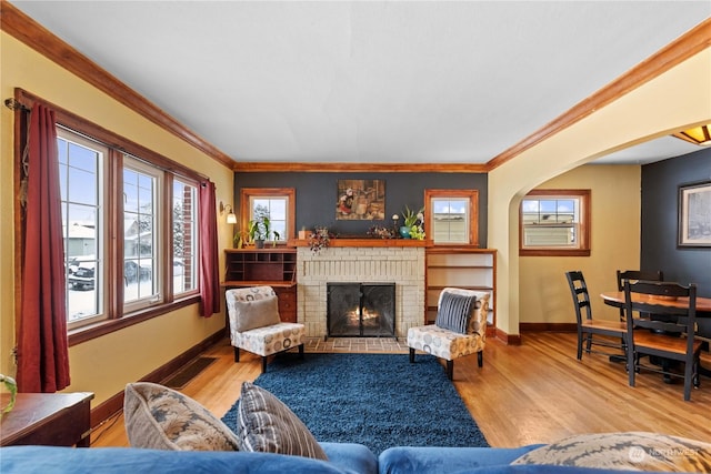 living room featuring a fireplace, light hardwood / wood-style floors, and ornamental molding