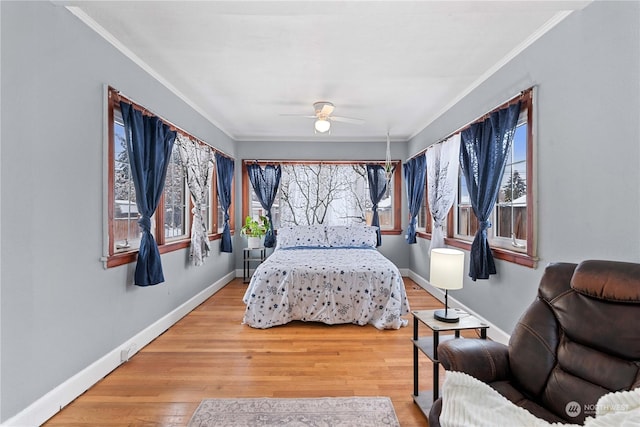 bedroom featuring hardwood / wood-style floors, multiple windows, crown molding, and ceiling fan