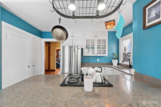 kitchen with white cabinetry, sink, stainless steel refrigerator, and black electric cooktop