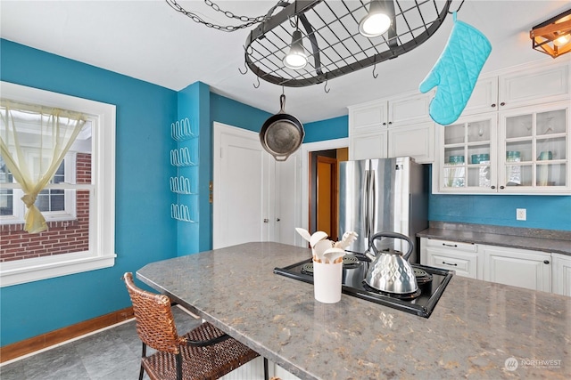 kitchen with stainless steel refrigerator, a kitchen breakfast bar, dark stone counters, black electric cooktop, and white cabinets