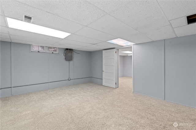 basement with a paneled ceiling and light colored carpet