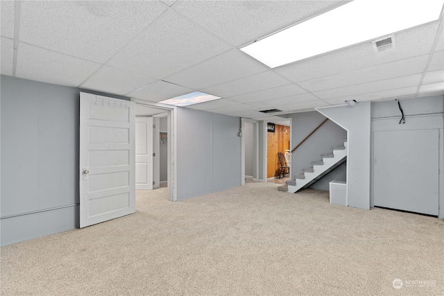 basement featuring light carpet and a drop ceiling