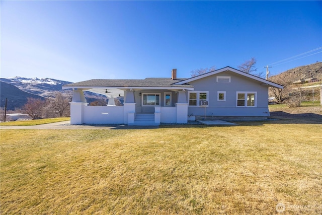 rear view of house with a mountain view, a lawn, and a chimney