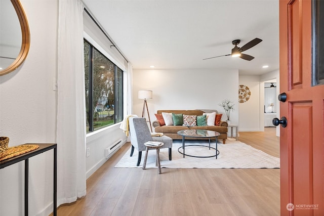 living room featuring ceiling fan, light wood-type flooring, and baseboard heating