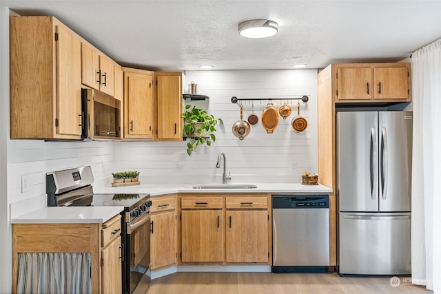 kitchen featuring sink, a textured ceiling, appliances with stainless steel finishes, and light wood-type flooring