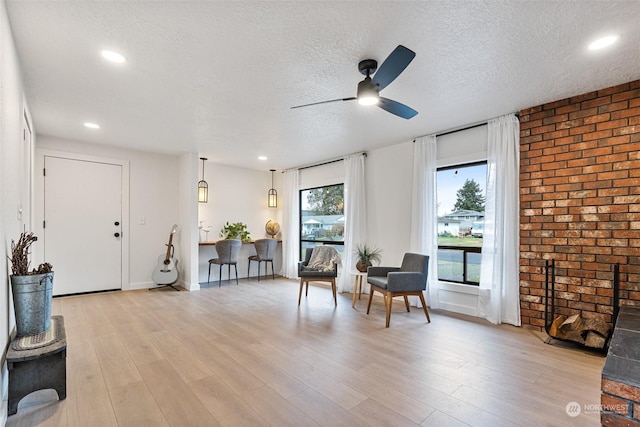 sitting room with ceiling fan, light hardwood / wood-style floors, and a textured ceiling