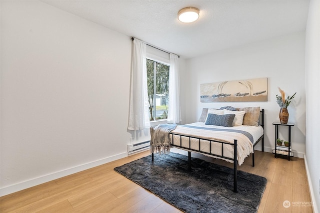 bedroom featuring a baseboard heating unit and hardwood / wood-style floors