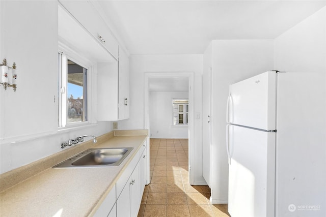 kitchen featuring sink, white cabinets, light tile patterned flooring, and white refrigerator