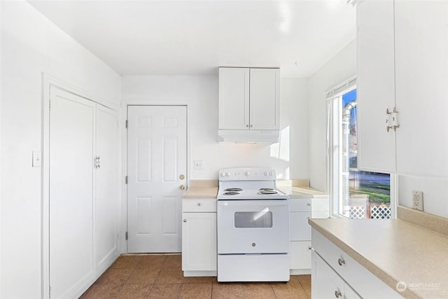 kitchen with white electric range oven, light tile patterned floors, and white cabinets