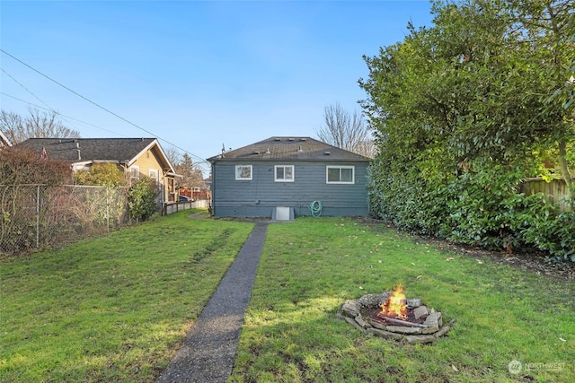 back of house with a lawn and a fire pit