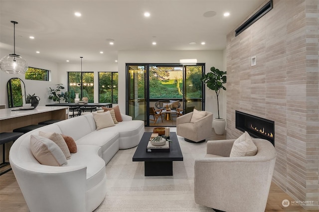 living room featuring light wood-type flooring and a tiled fireplace