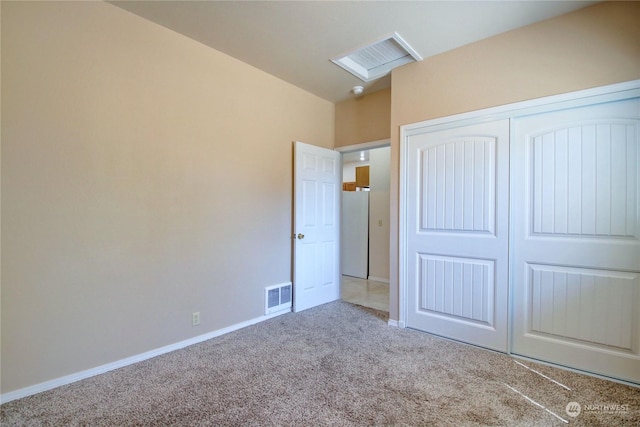 unfurnished bedroom featuring white fridge, carpet floors, and a closet