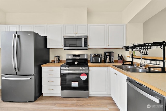 kitchen featuring sink, white cabinets, stainless steel appliances, and light wood-type flooring