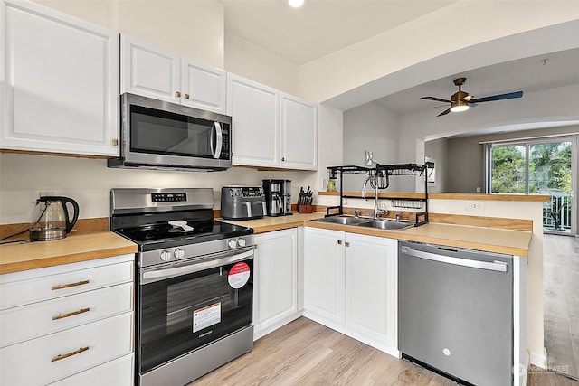 kitchen with white cabinets, sink, ceiling fan, appliances with stainless steel finishes, and kitchen peninsula