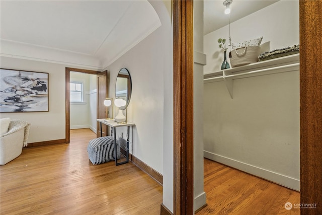 hallway featuring ornamental molding and light wood-type flooring