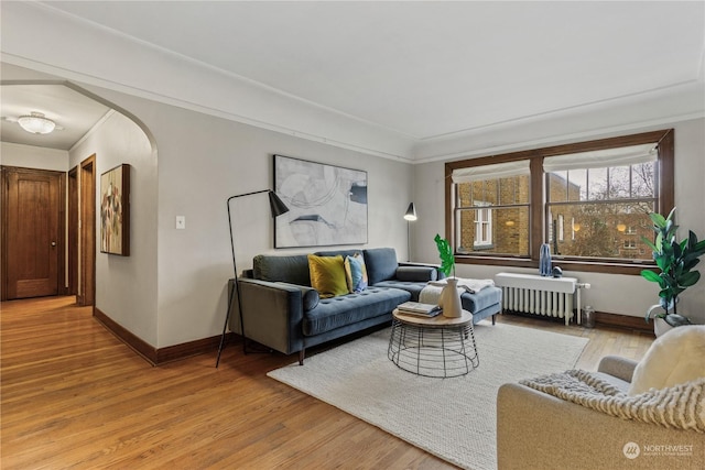 living room featuring hardwood / wood-style floors, crown molding, and radiator