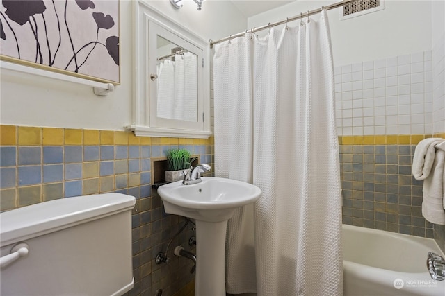 full bathroom with sink, shower / bath combination with curtain, tile walls, and toilet