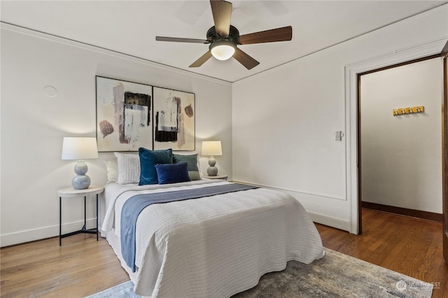 bedroom featuring ceiling fan, wood-type flooring, and ornamental molding