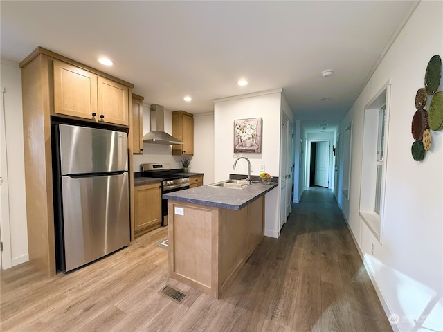 kitchen with wall chimney exhaust hood, light brown cabinets, stainless steel appliances, sink, and light hardwood / wood-style flooring