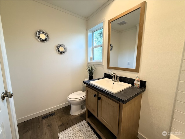 bathroom featuring hardwood / wood-style flooring, toilet, vanity, and crown molding