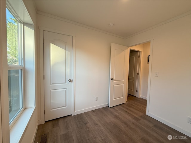 unfurnished bedroom featuring dark hardwood / wood-style flooring and crown molding