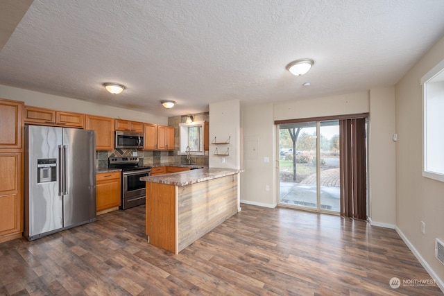 kitchen with stainless steel appliances, dark hardwood / wood-style floors, backsplash, kitchen peninsula, and a textured ceiling