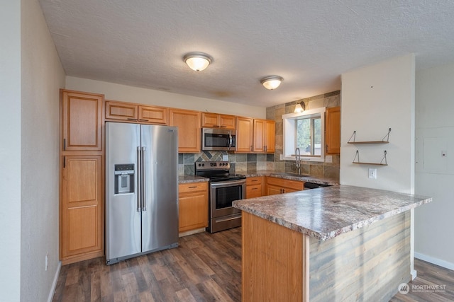 kitchen with dark wood-type flooring, sink, a textured ceiling, kitchen peninsula, and stainless steel appliances