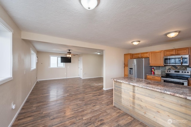 kitchen featuring backsplash, ceiling fan, a textured ceiling, dark hardwood / wood-style flooring, and stainless steel appliances