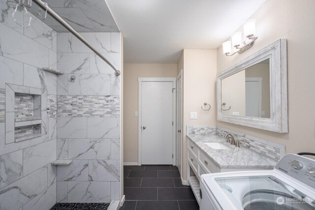 bathroom with tiled shower, washer / dryer, tile patterned flooring, and vanity