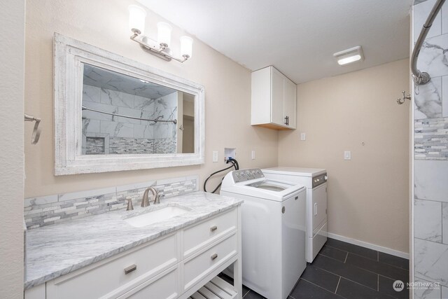 laundry room with washer and dryer, dark tile patterned floors, cabinets, and sink