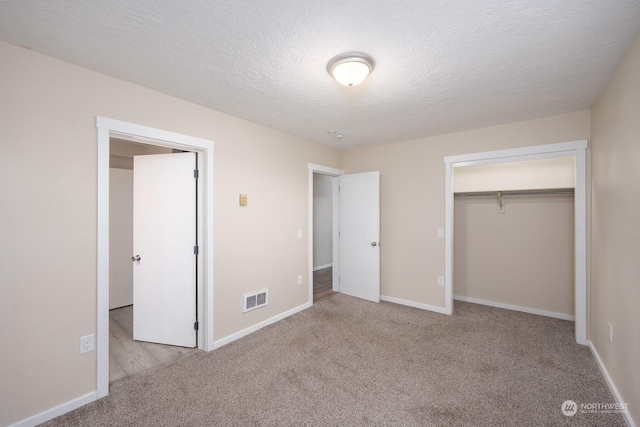 unfurnished bedroom featuring a textured ceiling, light colored carpet, and a closet