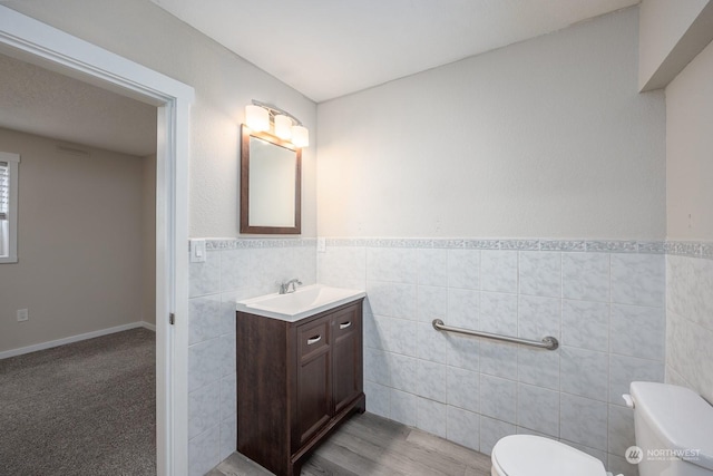 bathroom with hardwood / wood-style floors, vanity, toilet, and tile walls