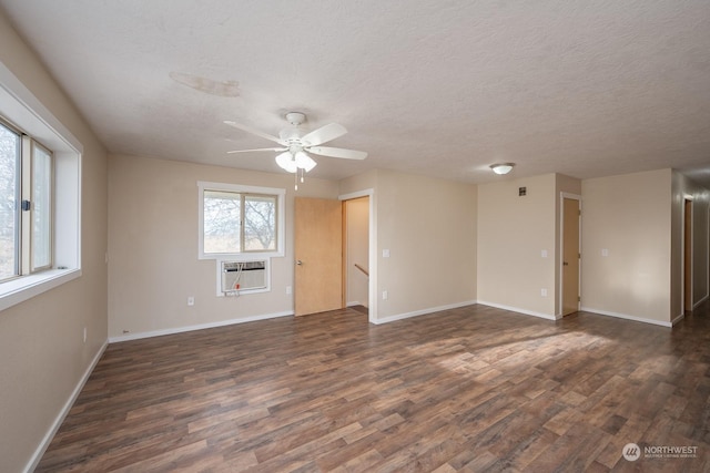 empty room with ceiling fan, dark hardwood / wood-style flooring, a textured ceiling, and a wall unit AC